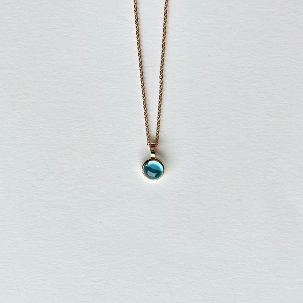 Gold charm with blue topaz